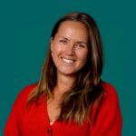 Authentiek zakelijk portret van een vrouw met een open glimlach en rode kleding voor een benaderbare uitstraling.